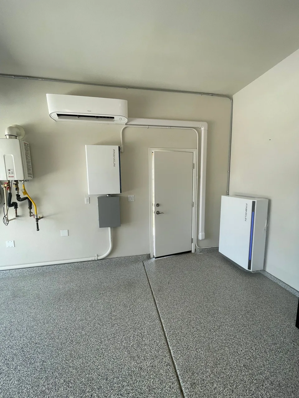 A Franklin control unit and battery mounted on opposite sides of an interior garage door, connected by conduit.