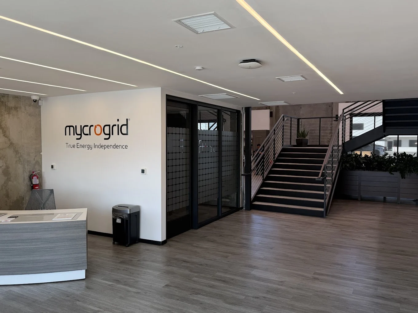 Mycrogrid® reception area with the company logo, front desk, and staircase in the Palm Desert office